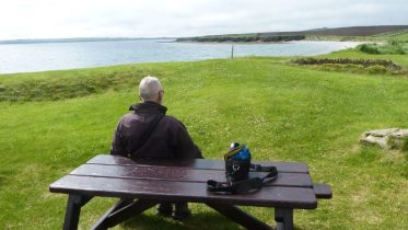 Sitting at picnic table at Ayre of the Myres, Stronsay